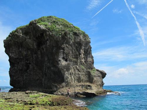 a large rock in the ocean with a man standing on it at 墾丁戀戀莎堡特色民宿 Castillo in Eluan