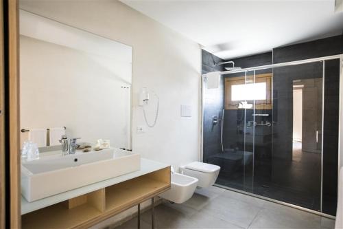 a bathroom with a sink and a toilet and a shower at Cave Bianche Hotel in Favignana