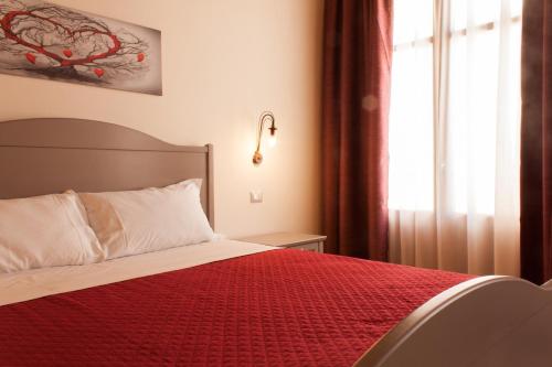 a bedroom with a bed with a red blanket and a window at Case Vacanze Al Duomo in Licata