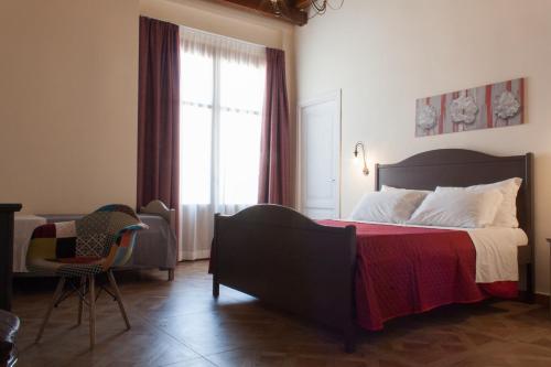 a bedroom with a bed and a chair and a window at Case Vacanze Al Duomo in Licata