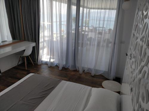 a bedroom with a bed and a window with white curtains at Epirus Hotel in Sarandë