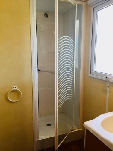 une douche en verre dans une salle de bain avec un lavabo dans l'établissement Camping Maureillas, à Maureillas