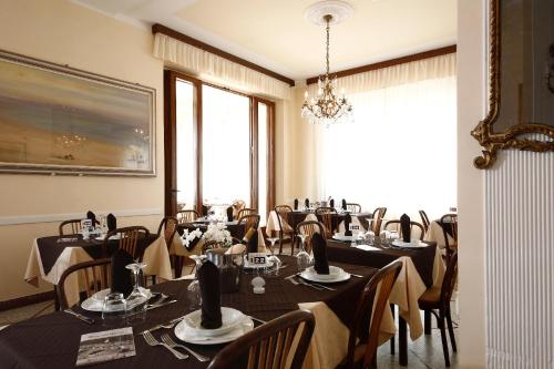 a dining room with tables and chairs and a chandelier at Hotel Villa Fulgida in Cattolica