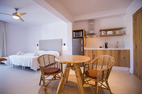 una habitación con una mesa y dos sillas y una cama en Sa Cala Suites, en Es Caló