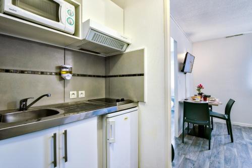 a small kitchen with a sink and a table at Zenitude Hôtel-Résidences Bordeaux Aéroport Mérignac in Mérignac