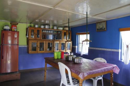 a kitchen with a table and a blue wall at Vamoose Orchid Villa Homestay in Rinchingpong