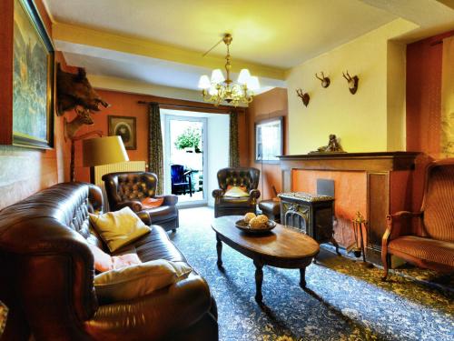 Very authentic Ardennes house في Paliseul: غرفة معيشة مع أريكة جلدية ومدفأة