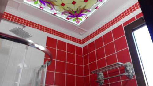 Baño de azulejos rojos con ventana y espejo en Domskazka, en Bruchim Qela' Alon