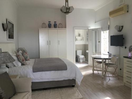 een slaapkamer met een bed, een bureau en een tafel bij The Good Life in Durban