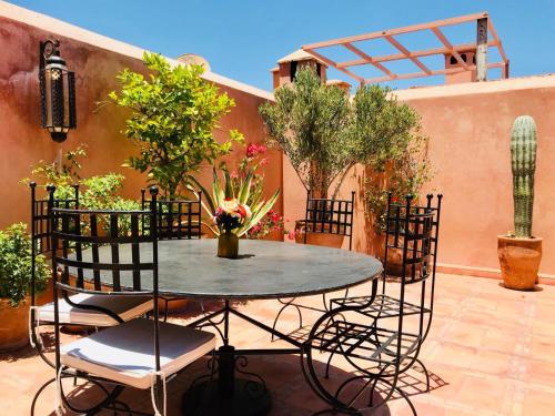 una mesa y sillas en un patio con plantas en Riad AKL en Marrakech