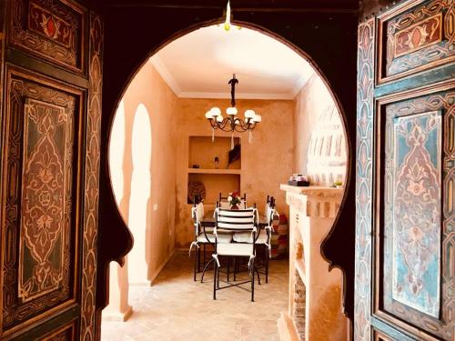 Un arco conduce a un comedor con mesa. en Riad AKL en Marrakech