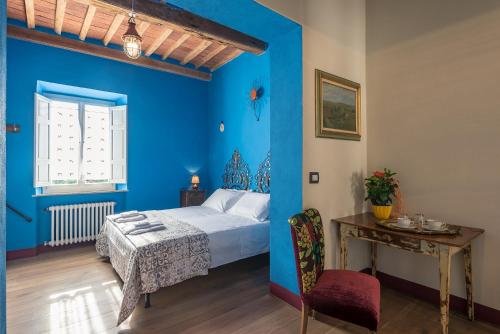 Schlafzimmer mit blauen Wänden, einem Bett und einem Tisch in der Unterkunft Civicouno Campiglia in Campiglia Marittima