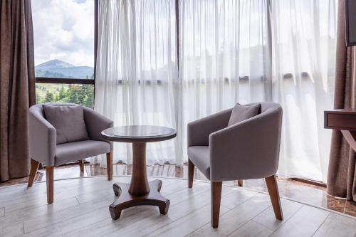 um quarto com duas cadeiras, uma mesa e uma janela em Carparosa Hotel em Bukovel