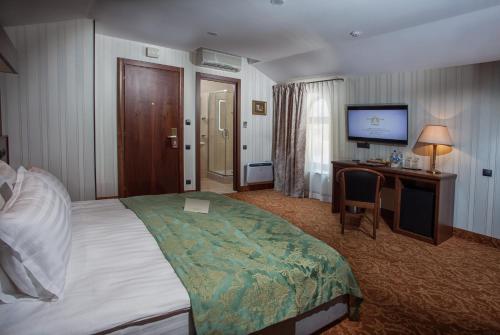 a hotel room with a bed and a desk and a television at Hotel Otrada in Odesa