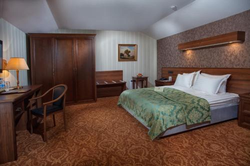 a hotel room with a bed, chair, desk and a lamp at Hotel Otrada in Odesa