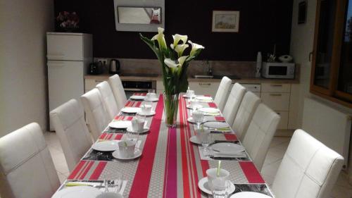 a long table with white chairs and a red and white table cloth at Chambres d'hôtes La Rive - Le Mont Saint Michel in Ardevon