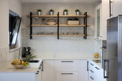 a kitchen with white cabinets and shelves on the wall at New Mountainside Villa w Pool + Stunning Sea View in Makarska