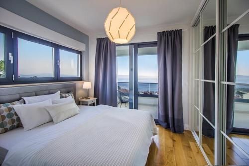 a bedroom with a large bed with large windows at New Mountainside Villa w Pool + Stunning Sea View in Makarska