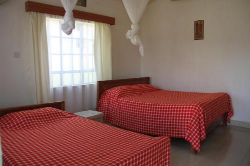 two beds in a room with red and white sheets at Sandai Resort Lake Baringo in Ol Kokwe