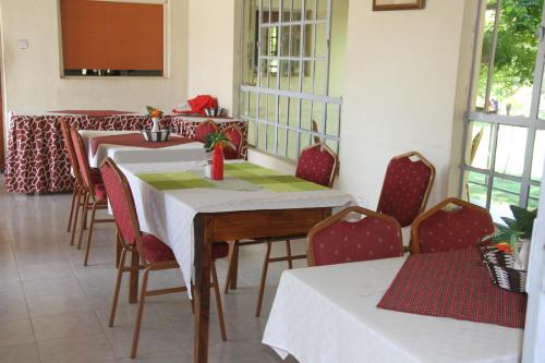 Ol KokweにあるSandai Resort Lake Baringoのダイニングルーム(テーブル2台、赤い椅子付)