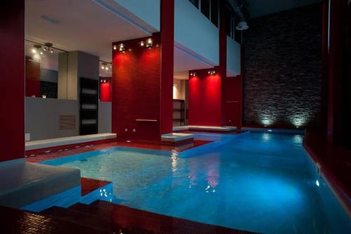 a large swimming pool in a room with red lights at Hotel Rivè - Complesso Turistico Campo Smith in Bardonecchia