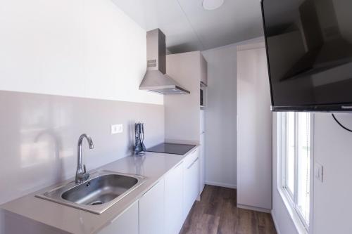 a kitchen with white cabinets and a sink at Camping Los Llanos in Denia
