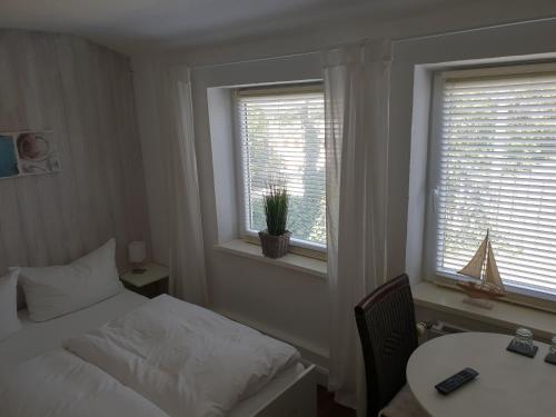 a bedroom with a bed and a table and two windows at Budget in Westerland (Sylt)