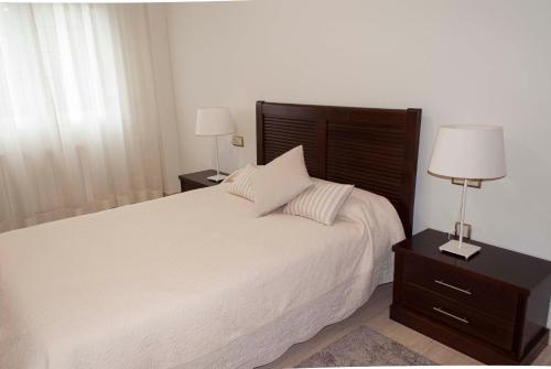 a bedroom with a large bed and two lamps on tables at Apartamento céntrico con parking privado in Córdoba