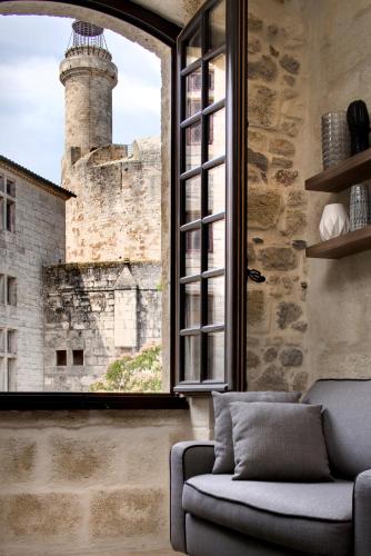 a room with a couch and a window with a lighthouse at Boutique Hôtel des Remparts & Spa in Aigues-Mortes