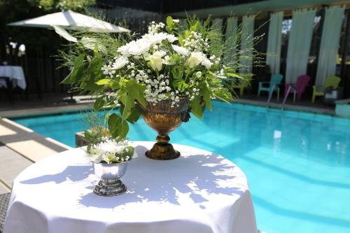a vase with flowers on a table next to a pool at Cors'Hotel in Biguglia