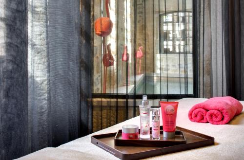 a tray of cosmetics sitting on top of a bed at Boutique Hôtel des Remparts & Spa in Aigues-Mortes