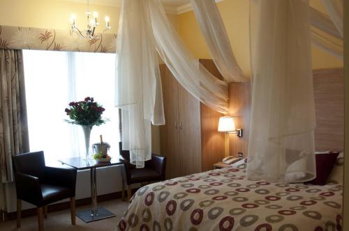 a bedroom with a bed and a table and a window at The Queensgate Hotel in Peterborough