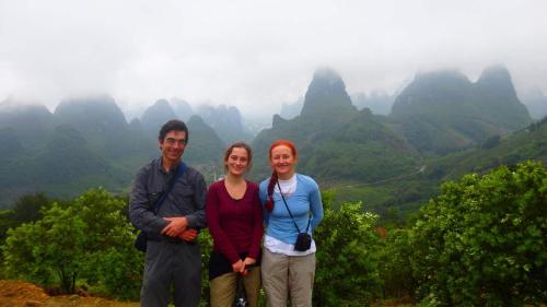 three people standing in front of a valley with mountains at Leisure Courtyard Hotel Yangshuo in Yangshuo