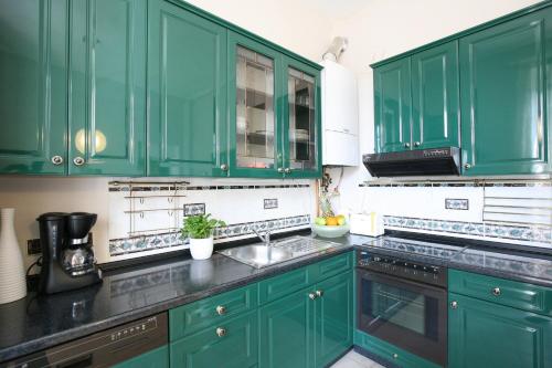eine grüne Küche mit grünen Schränken und einem Waschbecken in der Unterkunft Apartment Karolina in Prag