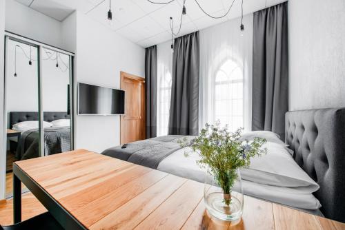 um quarto com uma cama e uma mesa com um vaso de flores em Piano Apartments em Kaunas