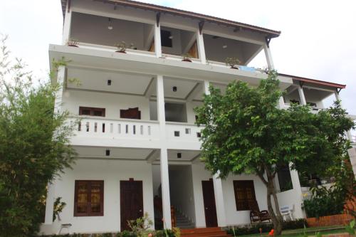 een wit gebouw met bomen ervoor bij Minh Kha Hotel in Mũi Né