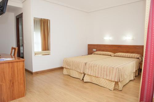 a bedroom with a bed and a table and a mirror at Hotel Las Anclas in El Astillero