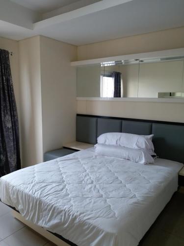 1 dormitorio con 1 cama blanca grande y espejo en Apartment Cosmo Terrace en Yakarta