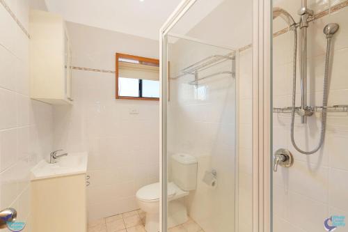 
a bathroom with a shower, toilet, and sink at Bayview Unit - Stunning Inlet Views in Narooma
