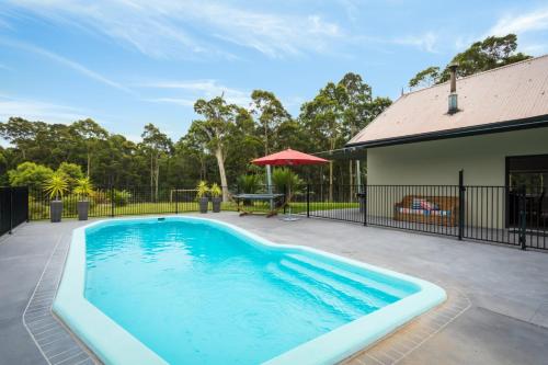 
a pool with a pool table and chairs in it at Bush Retreat With Private Pool in Narooma

