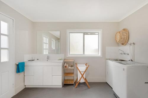 a white bathroom with a sink and a mirror at Bush Retreat With Private Pool in Narooma