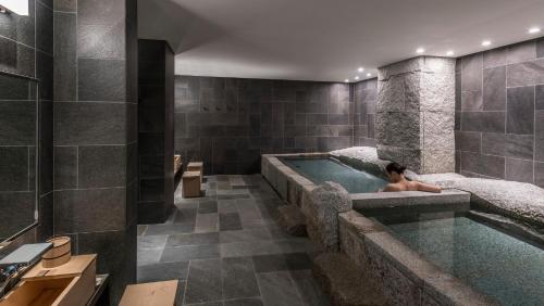 a woman laying in a bath tub in a bathroom at Four Seasons Hotel Kyoto in Kyoto