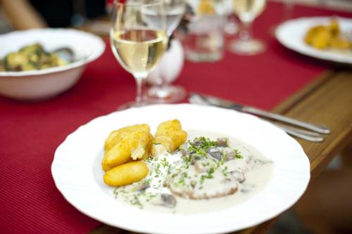 a white plate of food on a table with wine glasses at Gasthaus Straub in Grettstadt