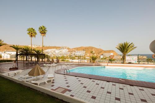 una piscina con tumbonas y palmeras en Apartamento Tobago, en Puerto Rico de Gran Canaria