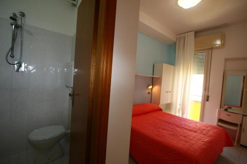 bagno con letto rosso e servizi igienici di Hotel Giannella a Rimini