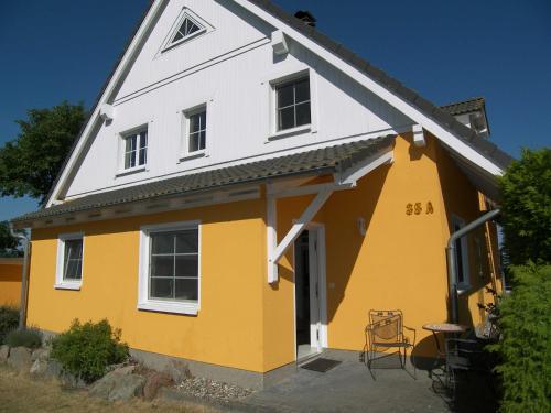 a yellow and white house with a table and a chair at Ferienwohnung Trassenheide in Trassenheide