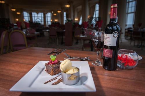 a plate of food and a bottle of wine on a table at Cumbria Grand Hotel in Grange Over Sands