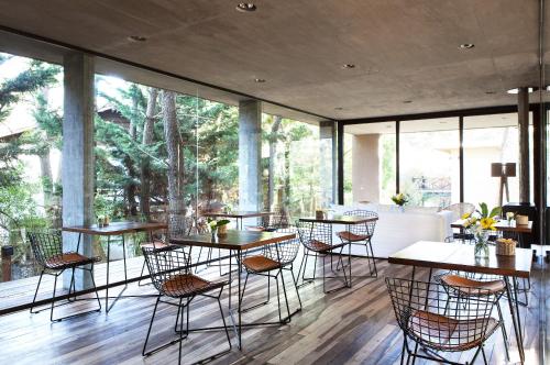 a dining room with tables and chairs and windows at Plenilunio Mar de las Pampas in Mar de las Pampas
