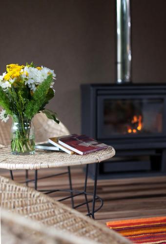 a vase of flowers on a table with a book at Plenilunio Mar de las Pampas in Mar de las Pampas