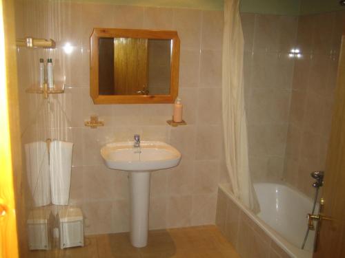 y baño con lavabo, espejo y bañera. en Cal Font (RCP), en Pla de Sant Tirs